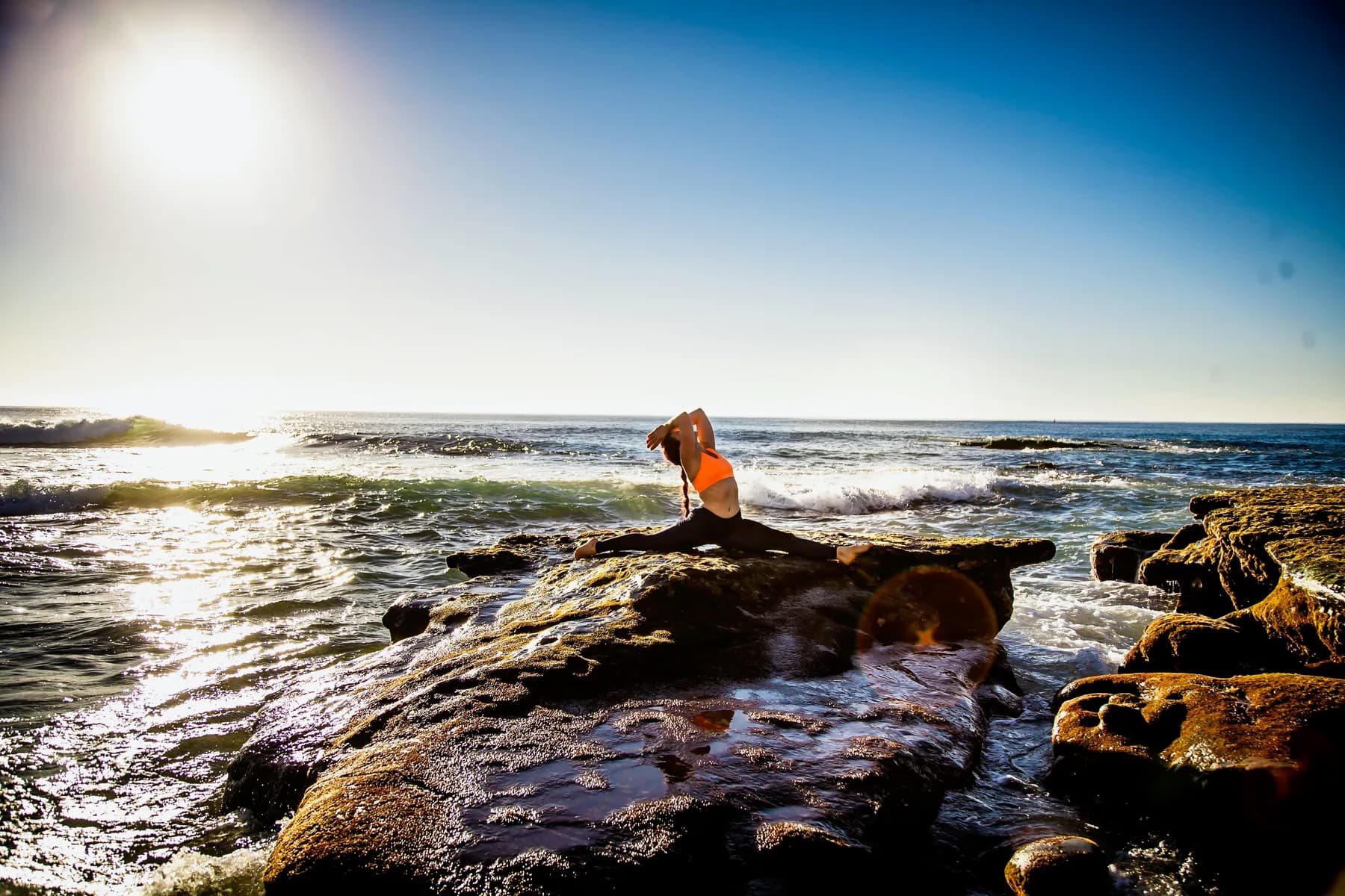 Hannahsita practicing a balanced movement pose on coastal rocks