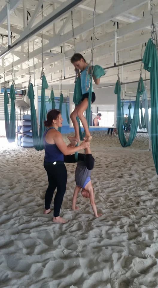 Hannahsita supporting two children as they explore movement with aerial fabric